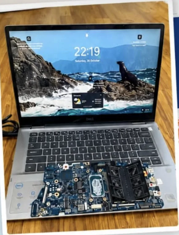 Dell Inspiron 5406 2-in-1 powered on with its replaced motherboard beside it
